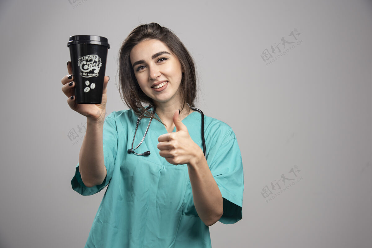 医院女医生拿着听诊器端着咖啡竖起大拇指高质量的照片医疗女性成人