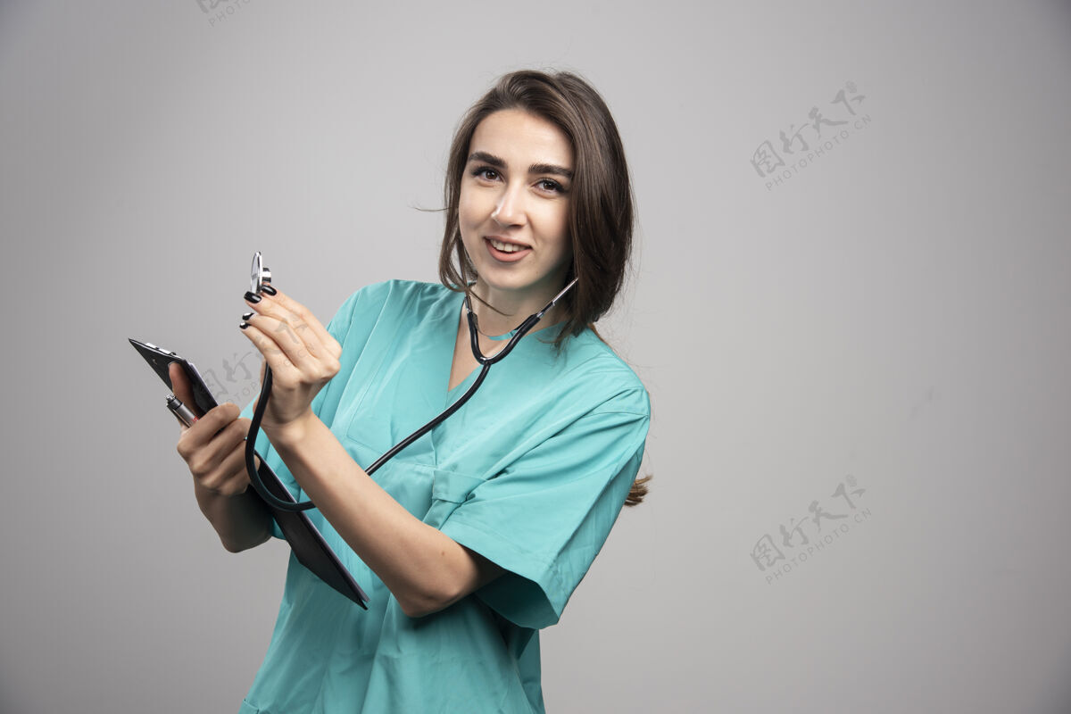 医疗女医生在灰色背景上使用听诊器高质量照片肖像成人工作