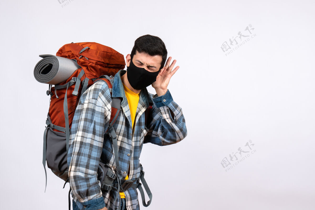 视图正面图年轻的旅行者背着背包和面具在听什么前面人背包
