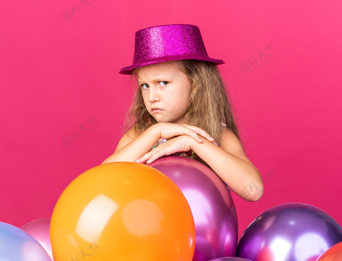 聚会恼怒的金发小女孩 戴着紫色的派对帽 站在粉色墙上的氦气球上 还有复制空间小恼火氦