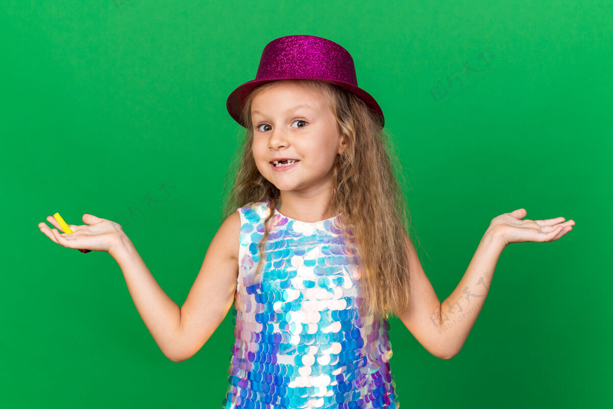 微笑微笑着的金发小女孩 戴着紫色的派对帽 手持派对哨子 手张开 在绿色的墙壁上与世隔绝 留着复制空间生日哨子帽子