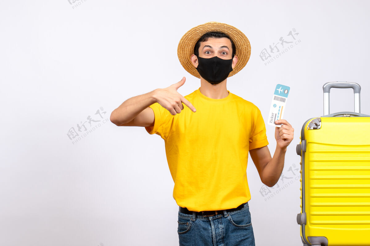 指向正面图戴草帽的大眼睛年轻人站在黄色手提箱旁指着机票帽子男性头饰