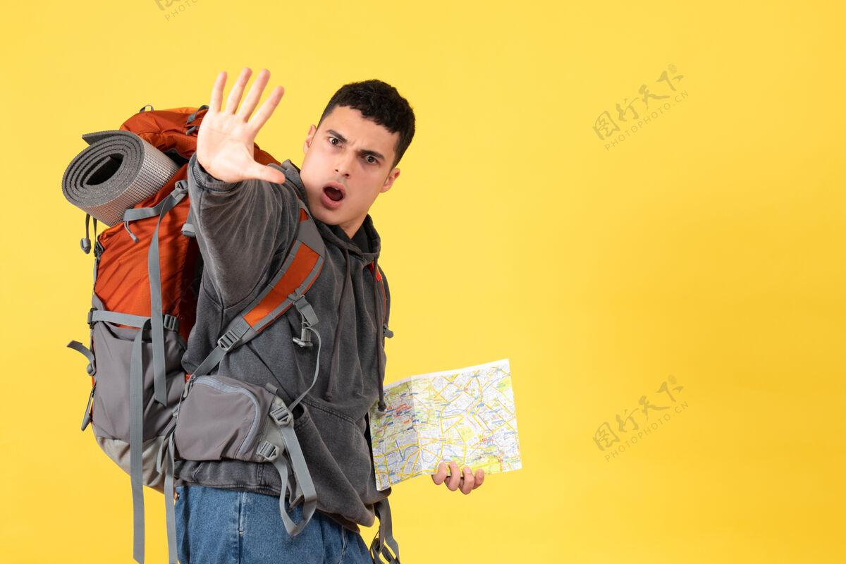 视图前视图旅行者男子背着背包拿着地图做停车标志人前面成人
