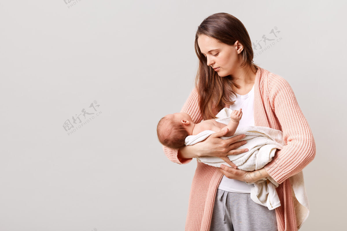 皮肤美丽的黑发母亲手里拿着新生婴儿天真健康新生儿