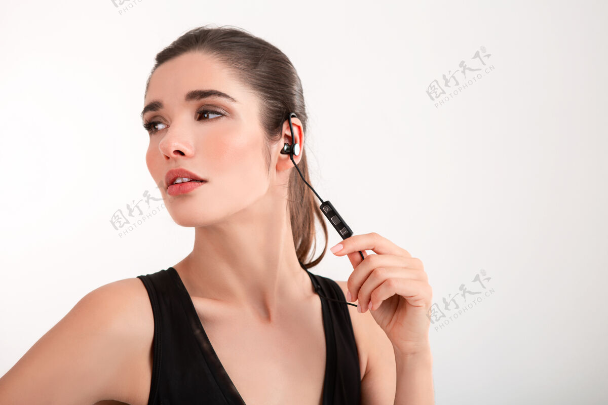 运动员穿着黑色上衣慢跑的黑发女人戴着耳机听音乐摆着灰色的姿势女性慢跑运动