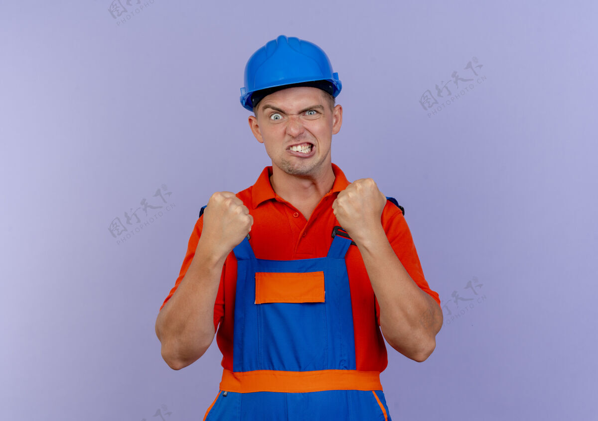 建筑工人快乐的年轻男性建筑工人穿着制服 戴着安全帽 表示同意年轻背景紫色