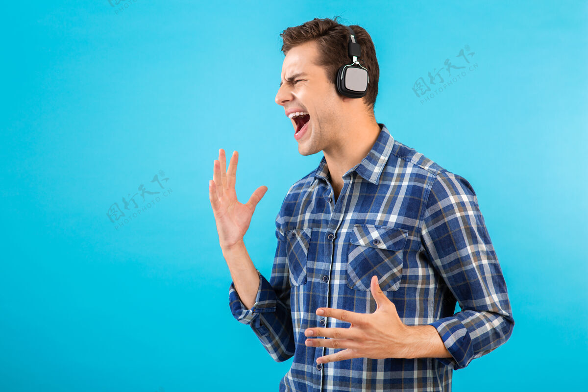 姿势坐在蓝色耳机上听音乐的男人的画像男性音频城市