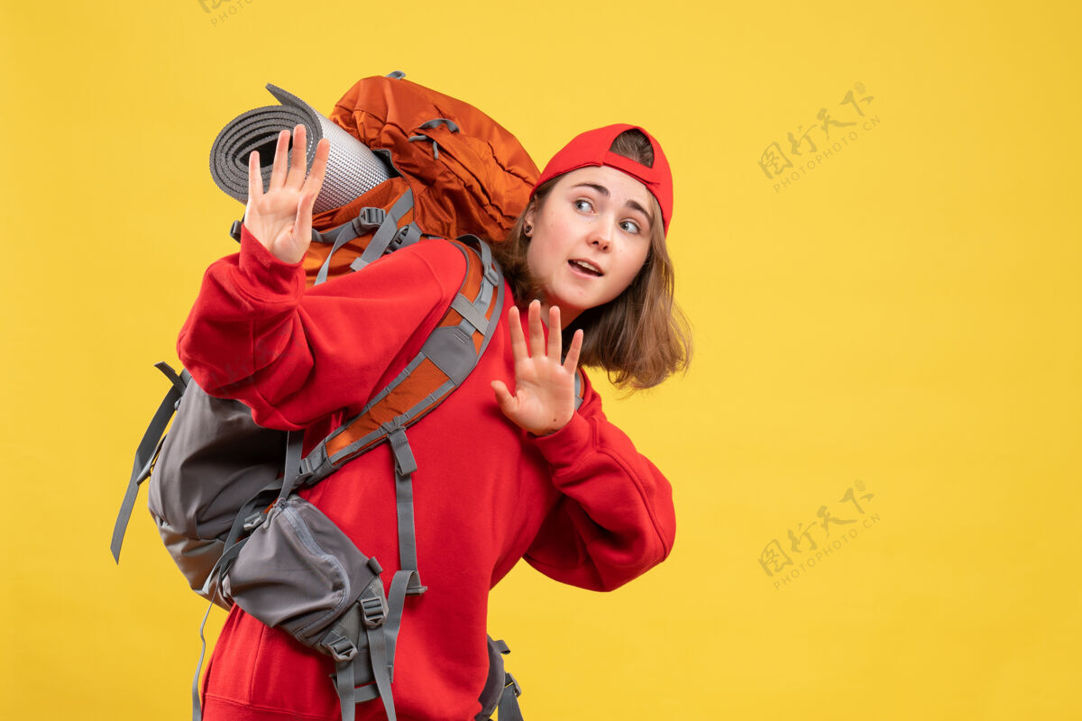 试试正面图年轻的旅行妇女在红色背包试图阻止什么背包前面站住