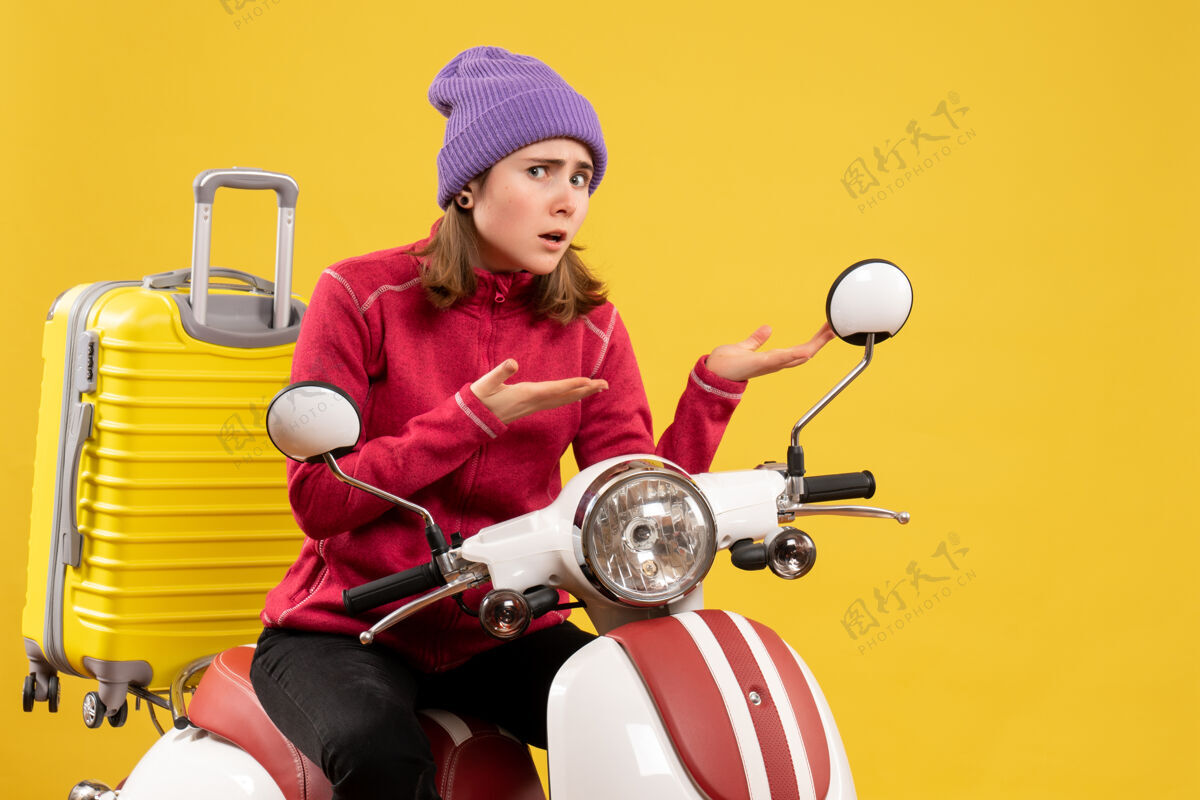 不舒服前视图坐在轻便摩托车上不安的年轻女孩指着什么东西坐着轻便摩托车摩托车