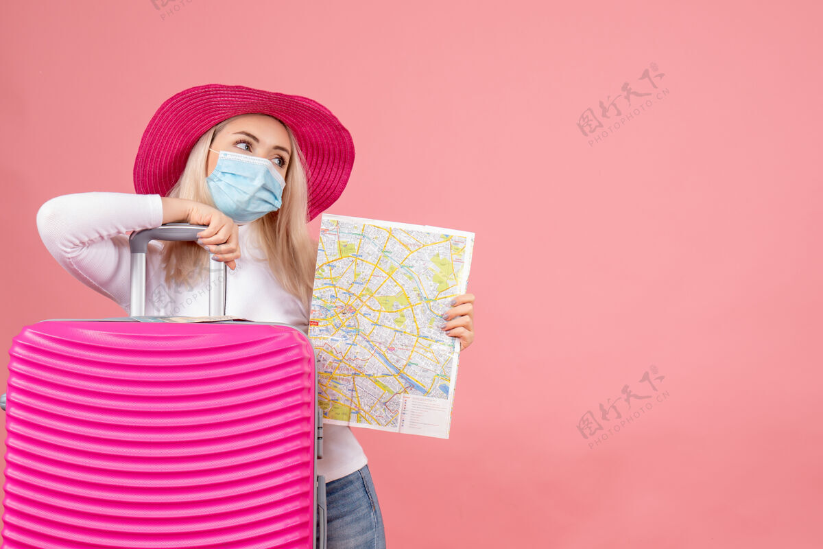 面具正面图戴着医用面罩的年轻女士站在手提箱旁拿着地图手提箱欢呼站