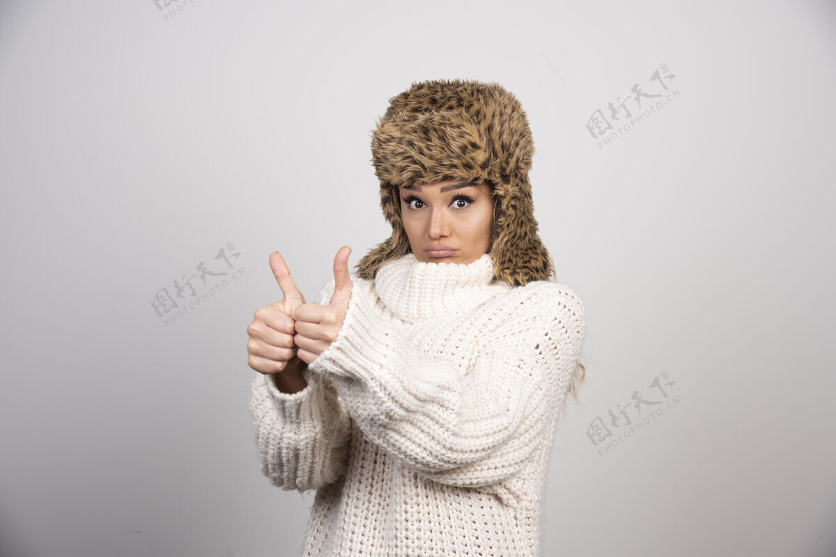 肖像穿白色针织毛衣的年轻女子竖起大拇指舒适女士女士