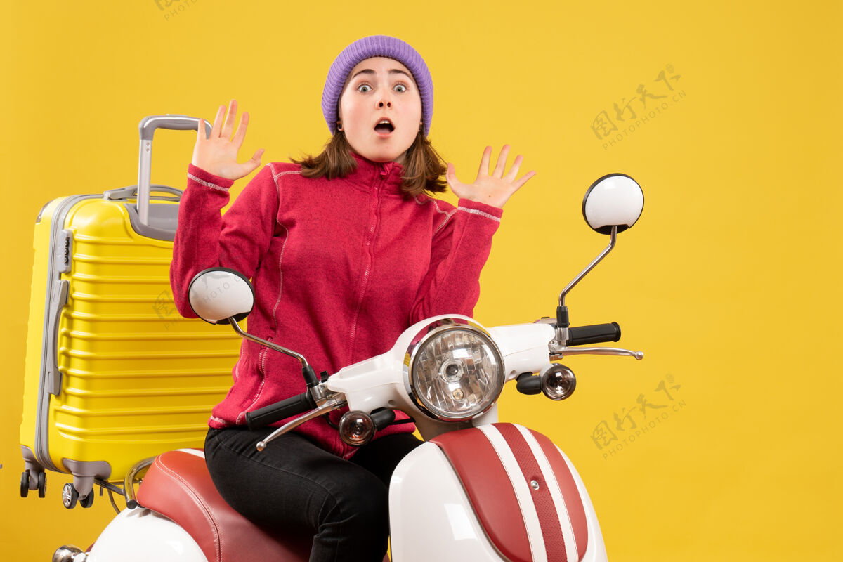 坐着前视图吓坏了坐在轻便摩托车上的年轻女孩举手妇女前面车辆