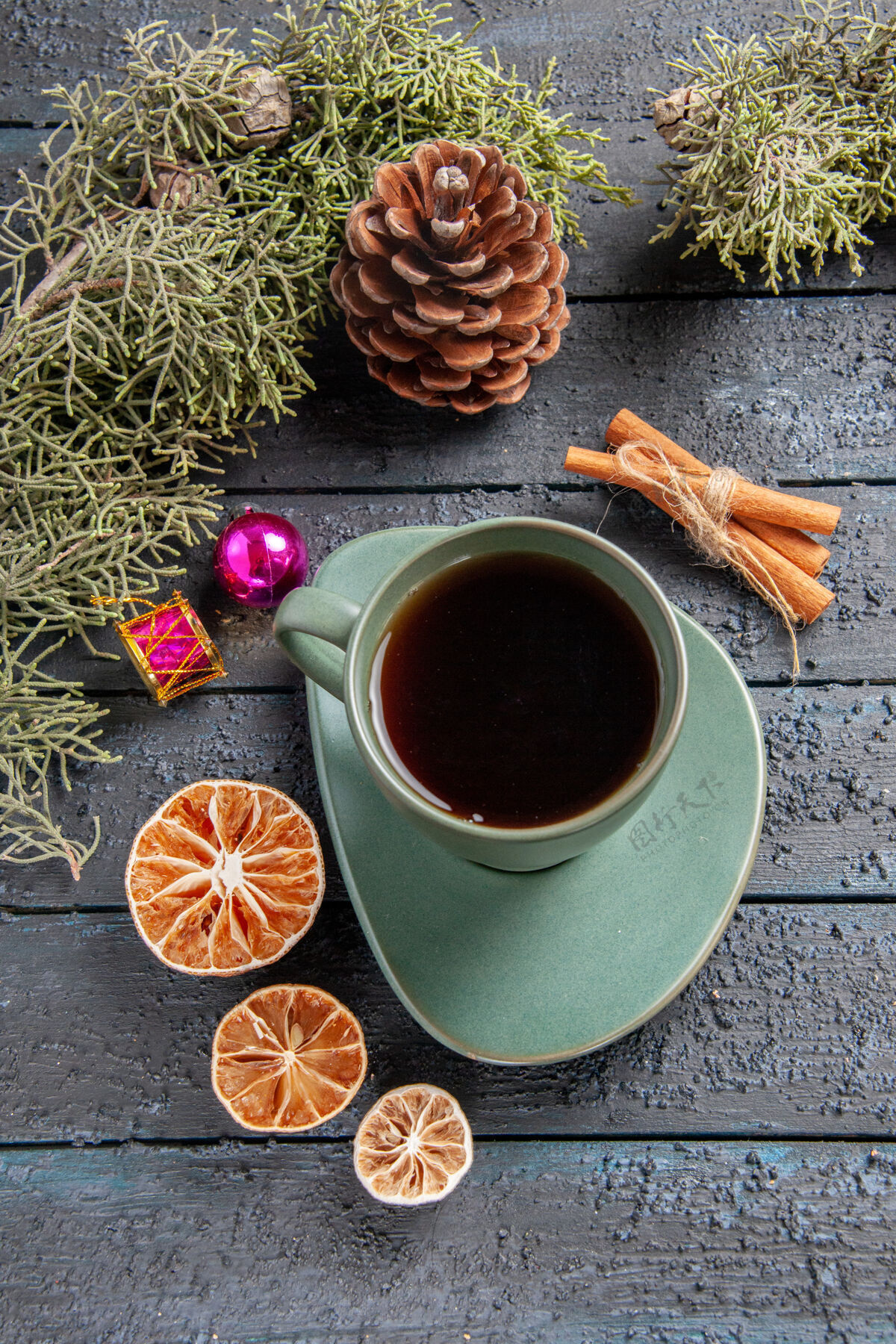 杯子顶视图一杯茶冷杉树枝圣诞玩具干橘子肉桂黑木桌上深色的肉桂咖啡因