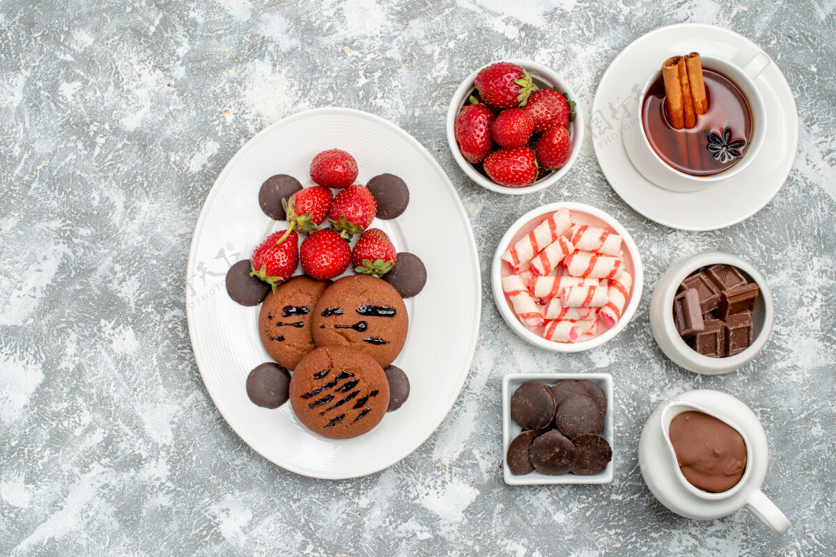 肉桂顶视图饼干草莓和巧克力碗可可糖草莓巧克力和茶与肉桂在右边的灰白色的桌子糖果草莓碗