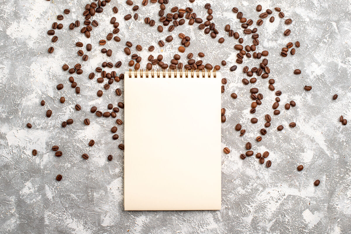 边框白色表面带有记事本的咖啡籽俯视图质地咖啡咖啡籽