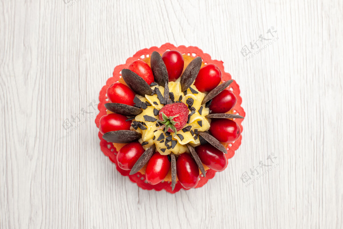 可食用的水果白色木桌上的红色椭圆形蕾丝doily巧克力蛋糕水果珠宝巧克力蛋糕