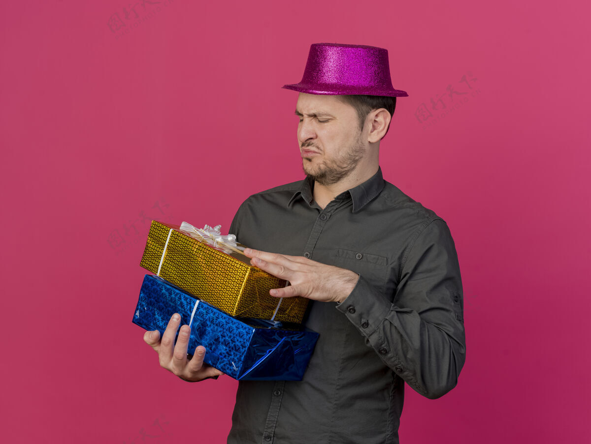 礼物一个戴着粉红色帽子的年轻人拿着礼物盒 看着孤立的粉红色盒子戴着粉色年轻人
