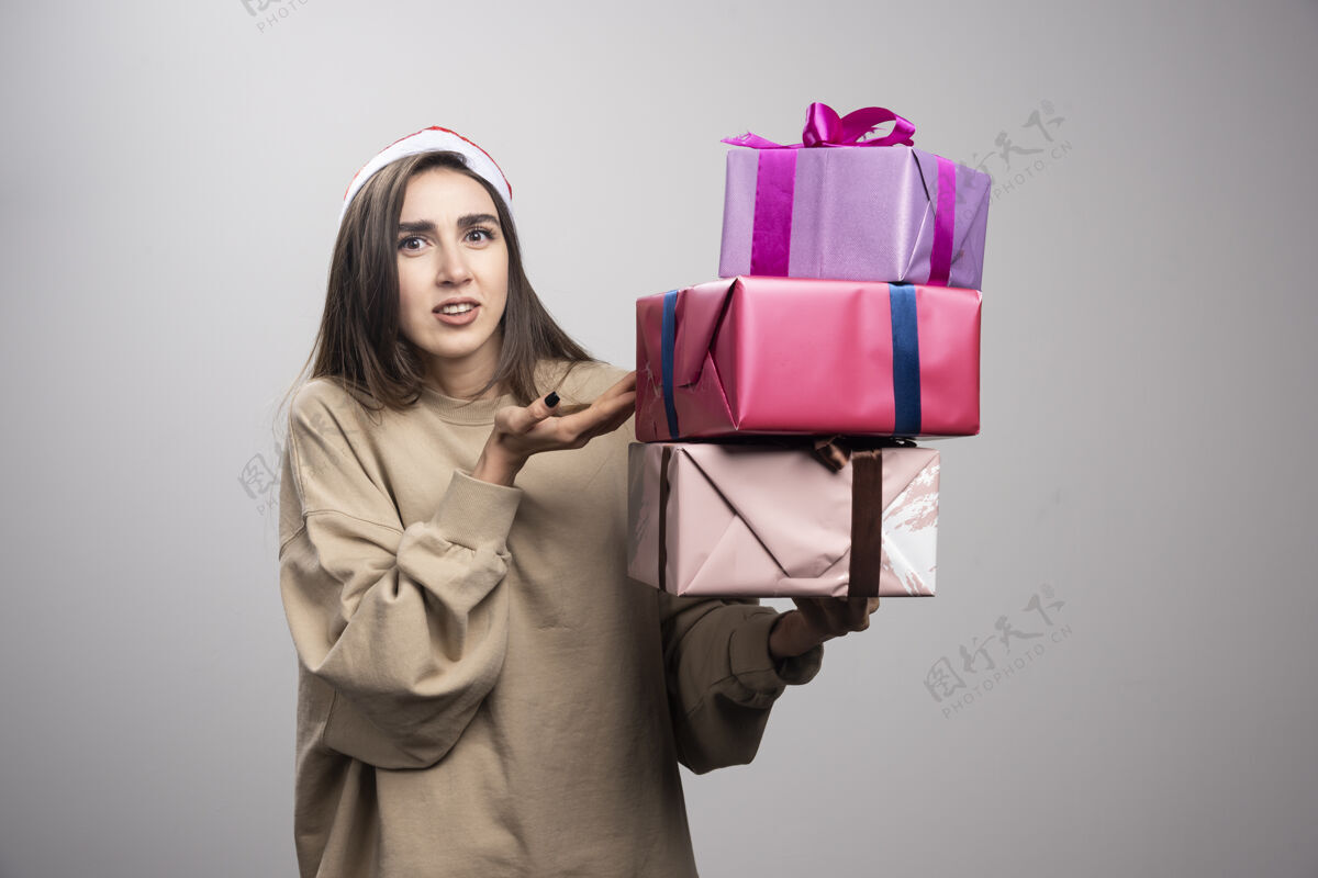 成人年轻女子手里拿着三盒圣诞礼物人站着礼物
