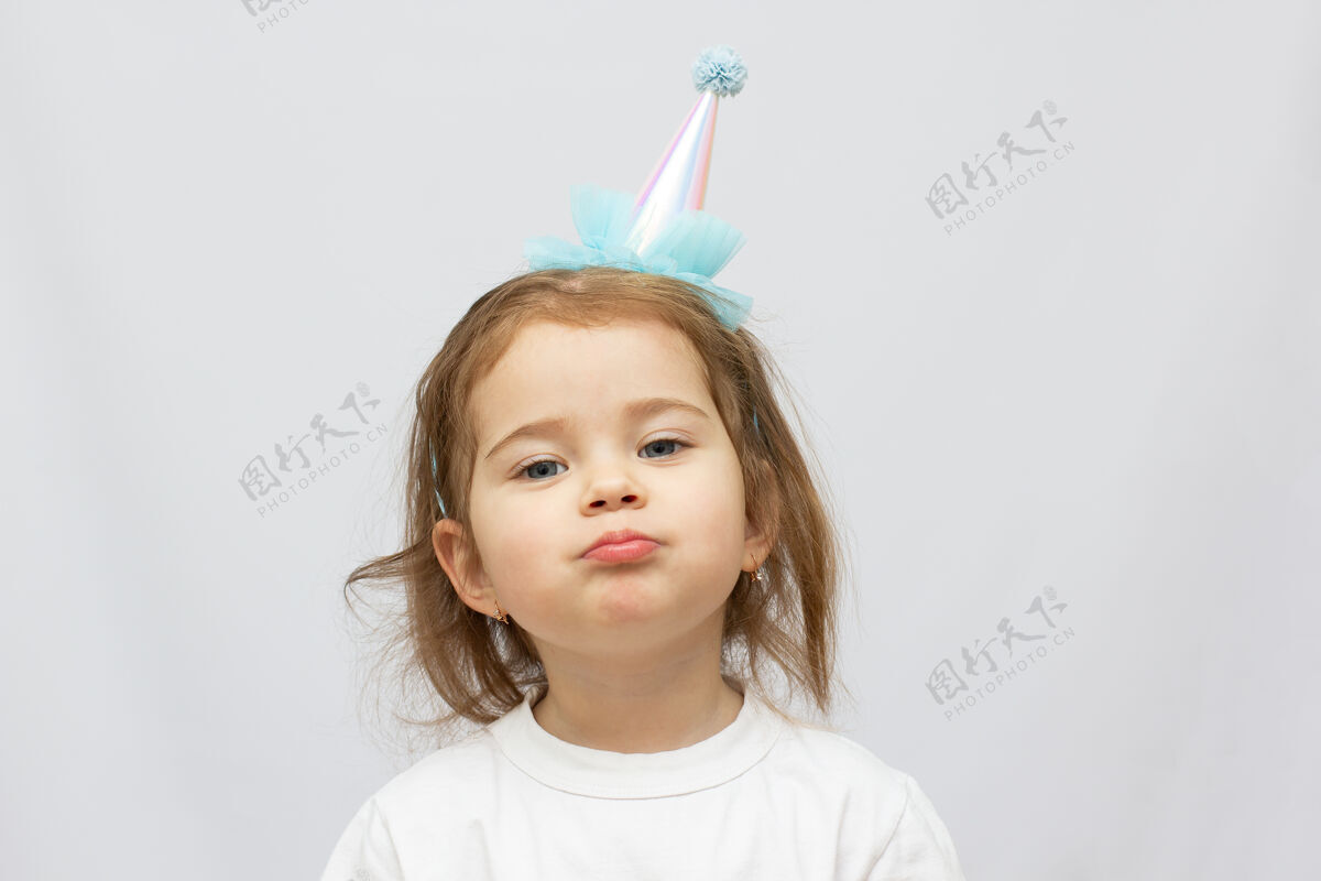 不快乐两岁金发碧眼的孩子 戴着派对帽 一张疲惫的白脸庆典累蹒跚学步