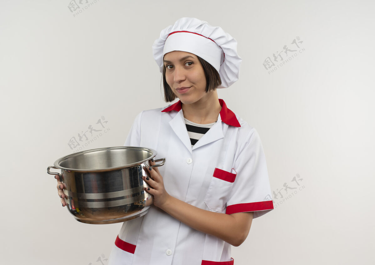 拿着高兴的年轻女厨师穿着厨师制服拿着锅看前面隔离的白墙上人年轻人