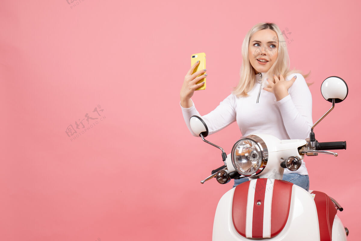 电话前视图满意的年轻女士骑着轻便摩托车拿着电话时尚表情欢乐