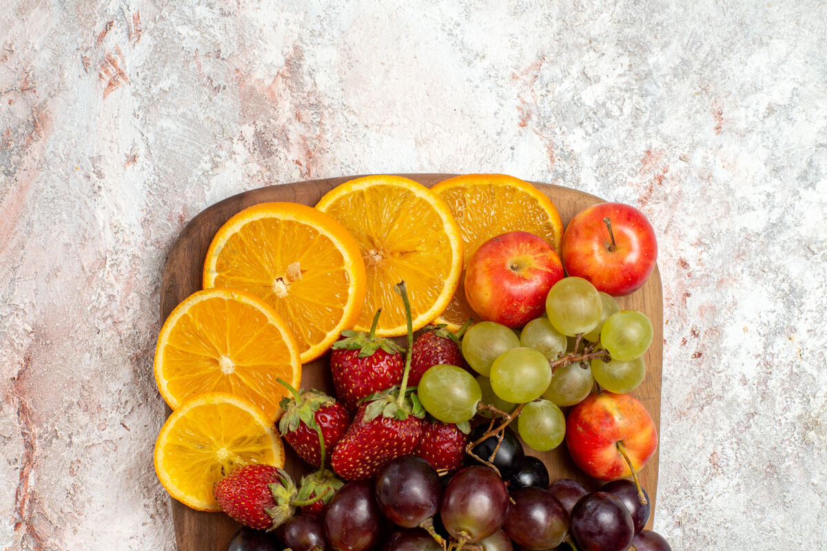 新鲜白色表面上新鲜水果成分橙子葡萄和草莓的俯视图新鲜水果组成成熟食品
