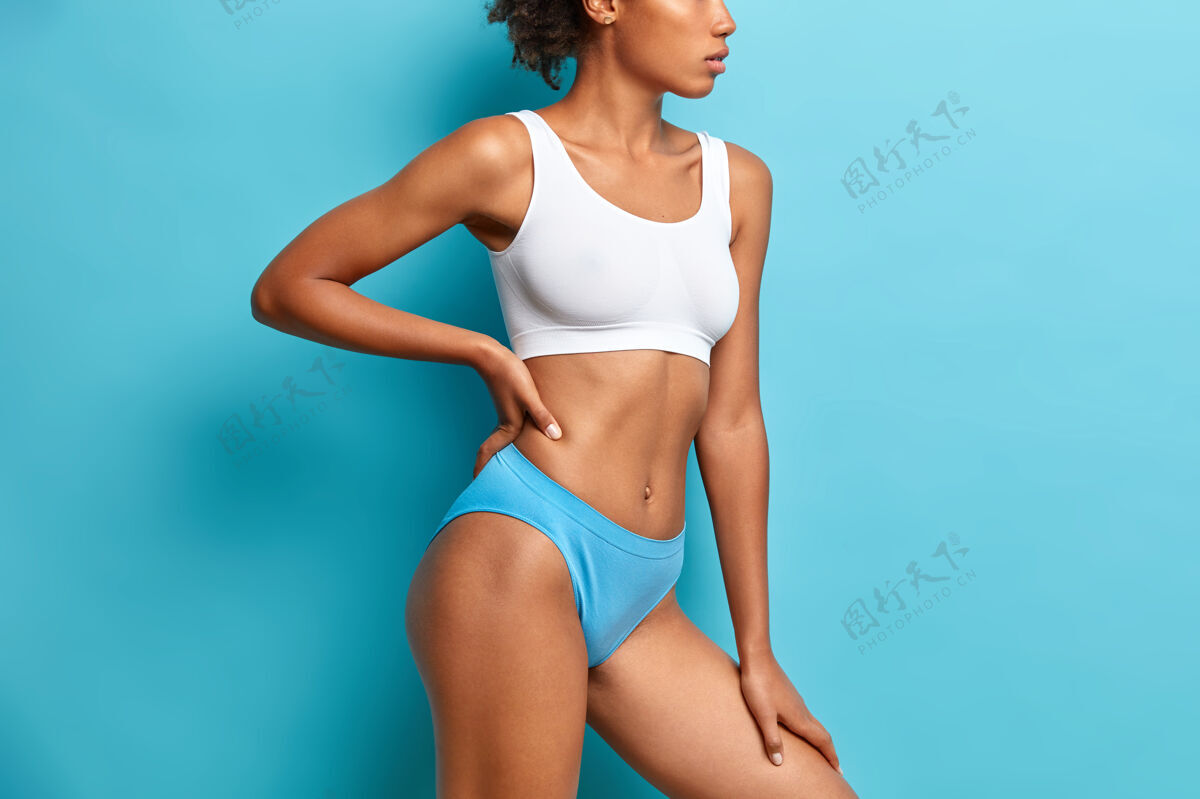 女人不可辨认的黑皮肤女人在短上衣和内裤有苗条的身材平坦的腹部显示出完美的身体后 减轻体重臀部立身形状