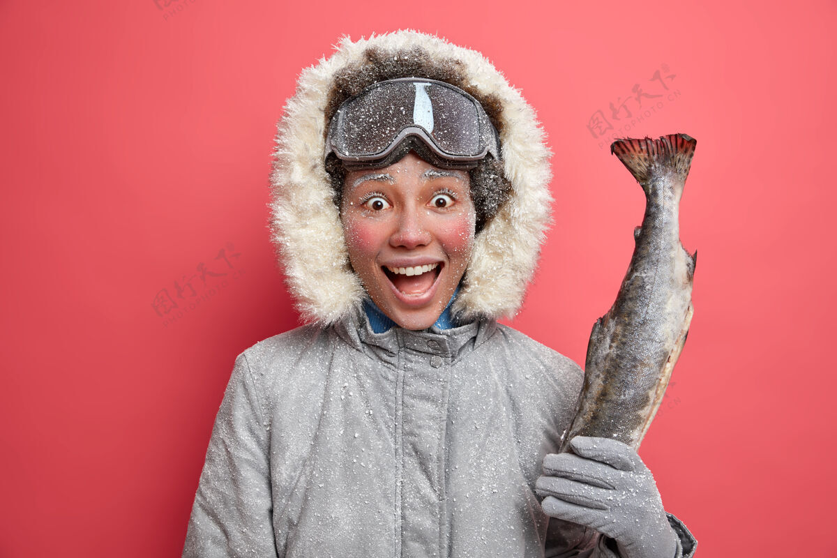 高兴积极的女人在冬天钓鱼穿着暖和的夹克戴滑雪板护目镜在低温下有积极的休息人欢呼手套