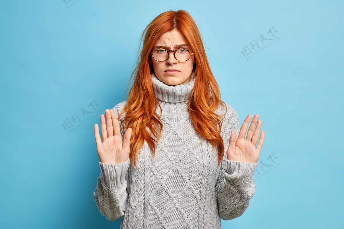眼镜严重不满红发女子显示停止手势提高手掌向穿着针织灰色毛衣女人人肖像