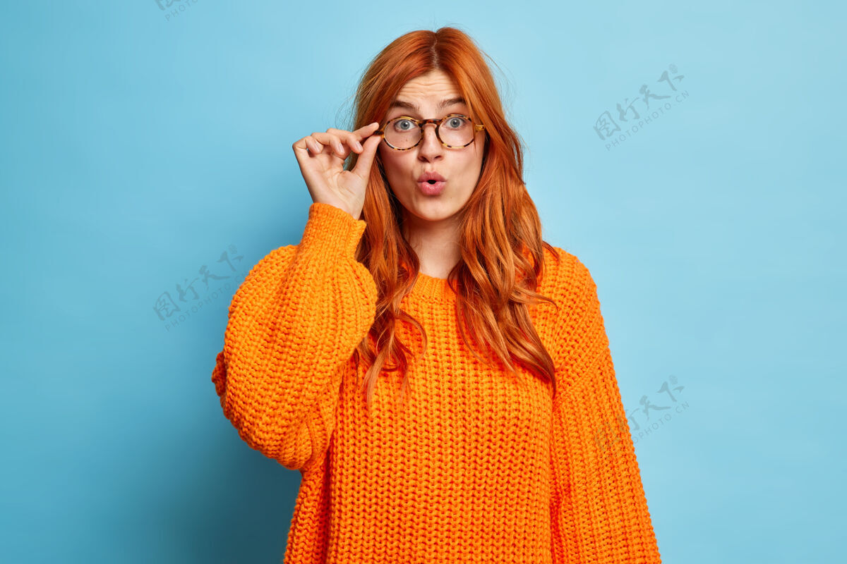 红发震惊无语的欧洲红发女子手戴眼镜 穿着针织橘色套头衫 惊奇地瞪大嘴巴 不经意间流露出情感女人生姜眼镜