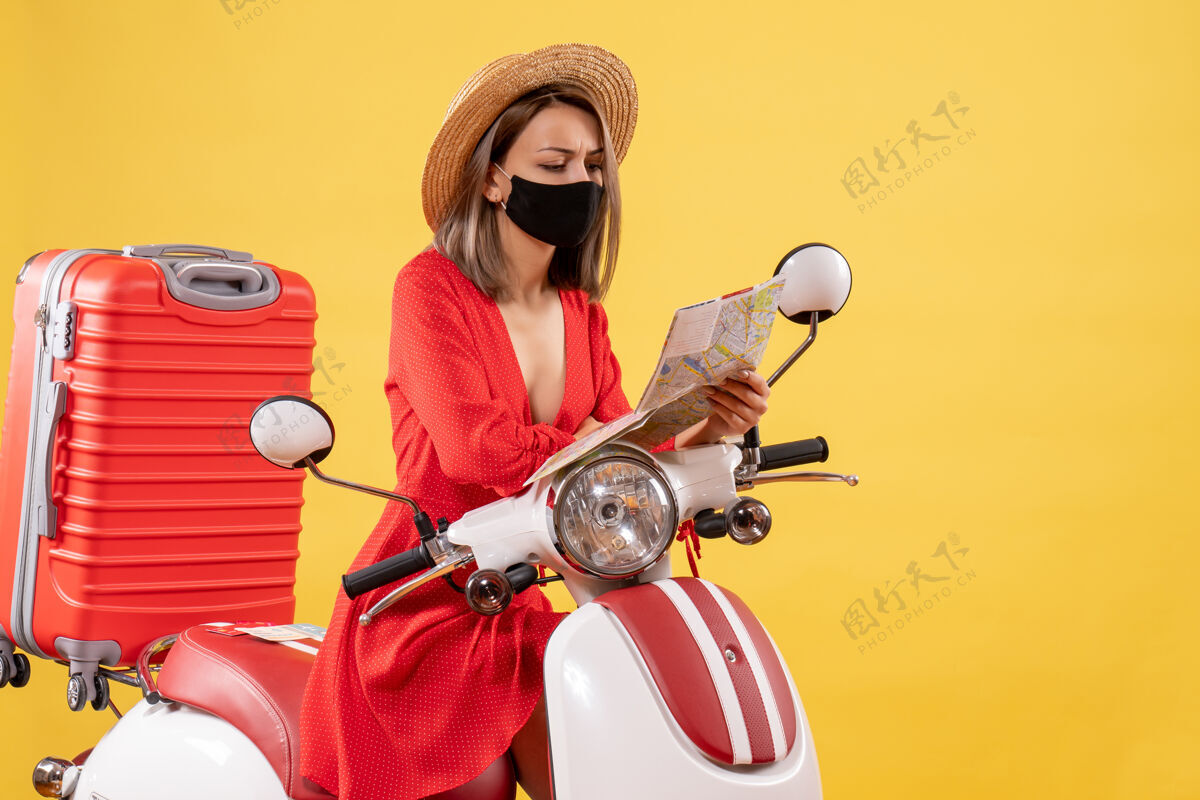 轻便摩托车戴着黑色面具的忙碌的年轻女士在看地图的前视图自行车前面人