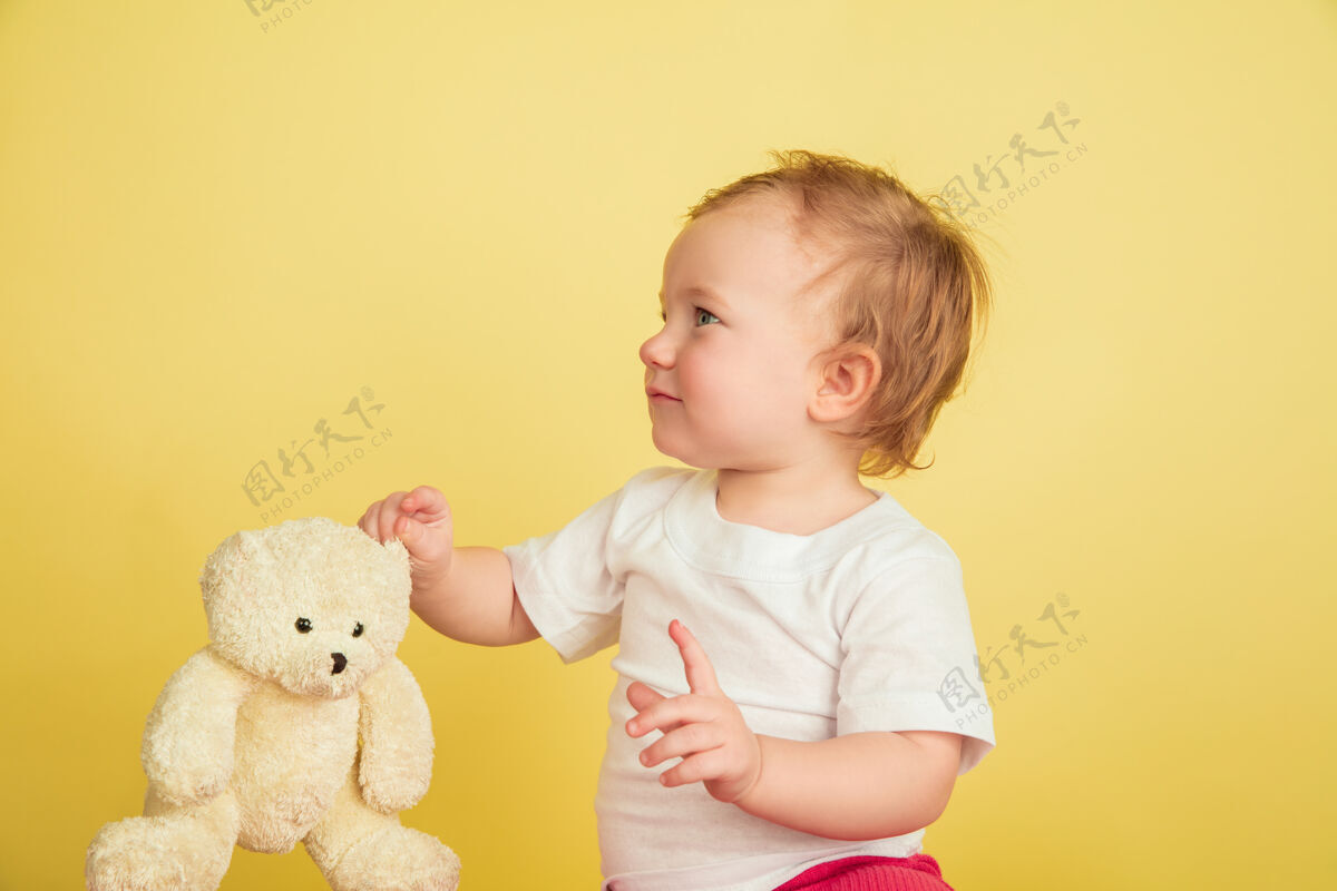 英俊白人小女孩 黄色工作室背景上孤立的孩子们可爱可爱的孩子的肖像 和泰迪熊玩耍的宝宝童年 家庭 幸福 新生活 教育的概念游戏生活家庭