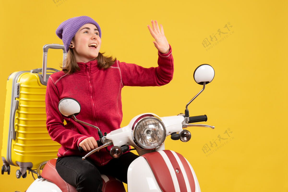 微笑前方是一个坐在轻便摩托车上挥手的快乐女孩球人摩托车
