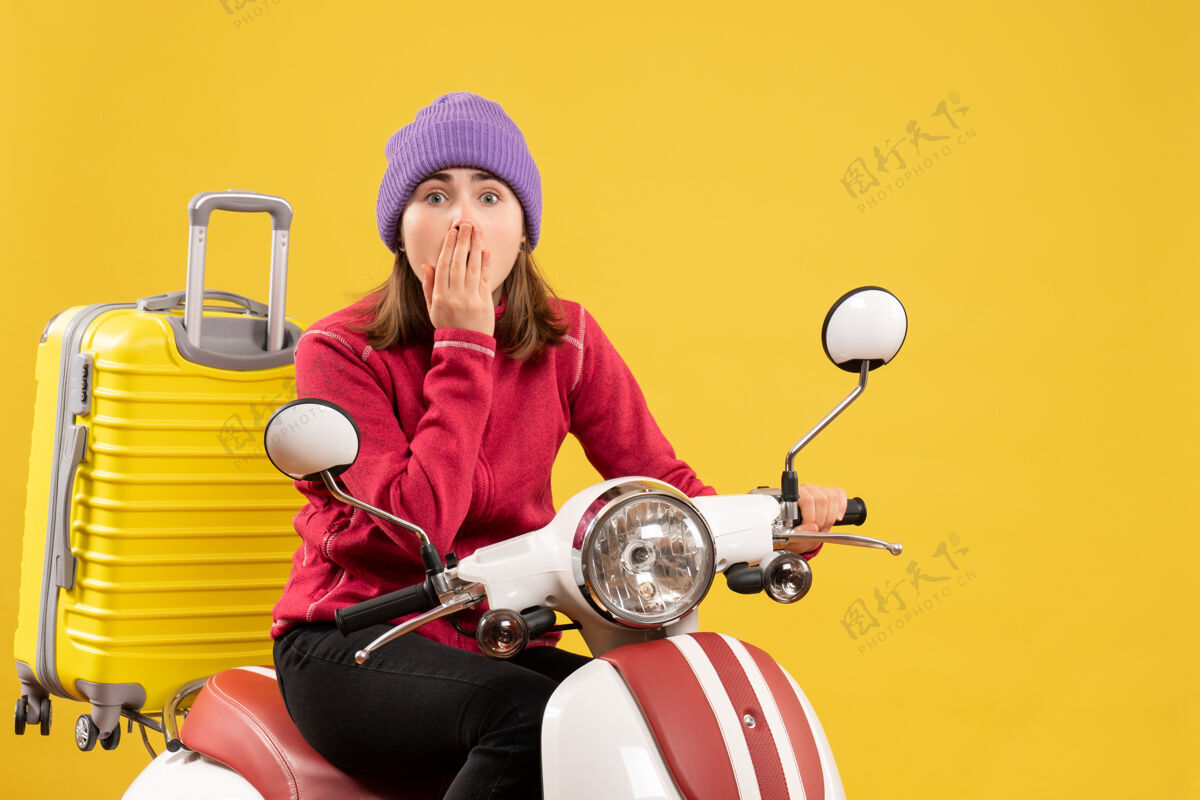 摩托车前视图惊愕地坐在轻便摩托车上的年轻女子看着前面车辆男微笑