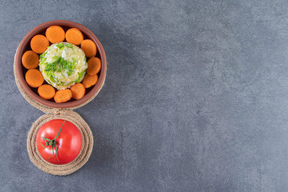 美味把胡萝卜片和首都沙拉放在一个碗里 旁边放着西红柿 放在蓝色的三角架上美味新鲜蔬菜