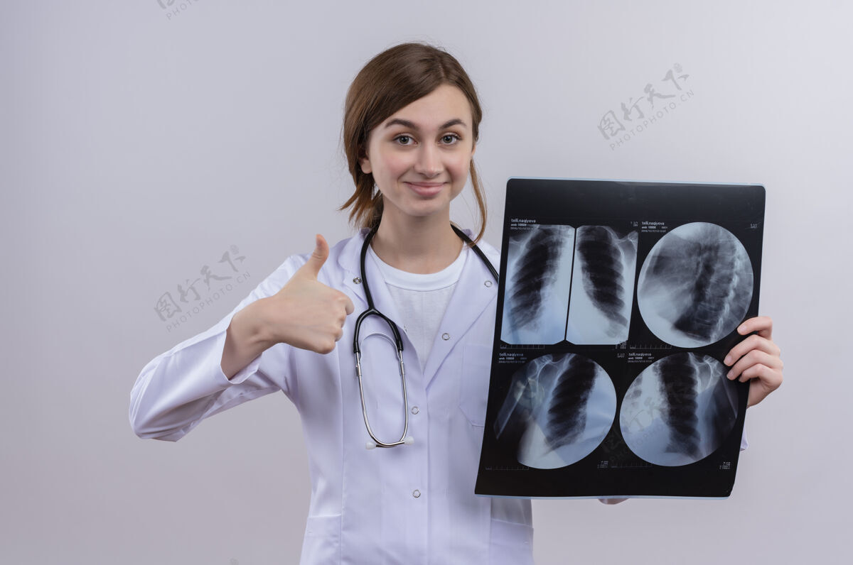 女年轻的女医生穿着医用长袍 手持听诊器 举着x光片 大拇指朝上拿着医生医疗