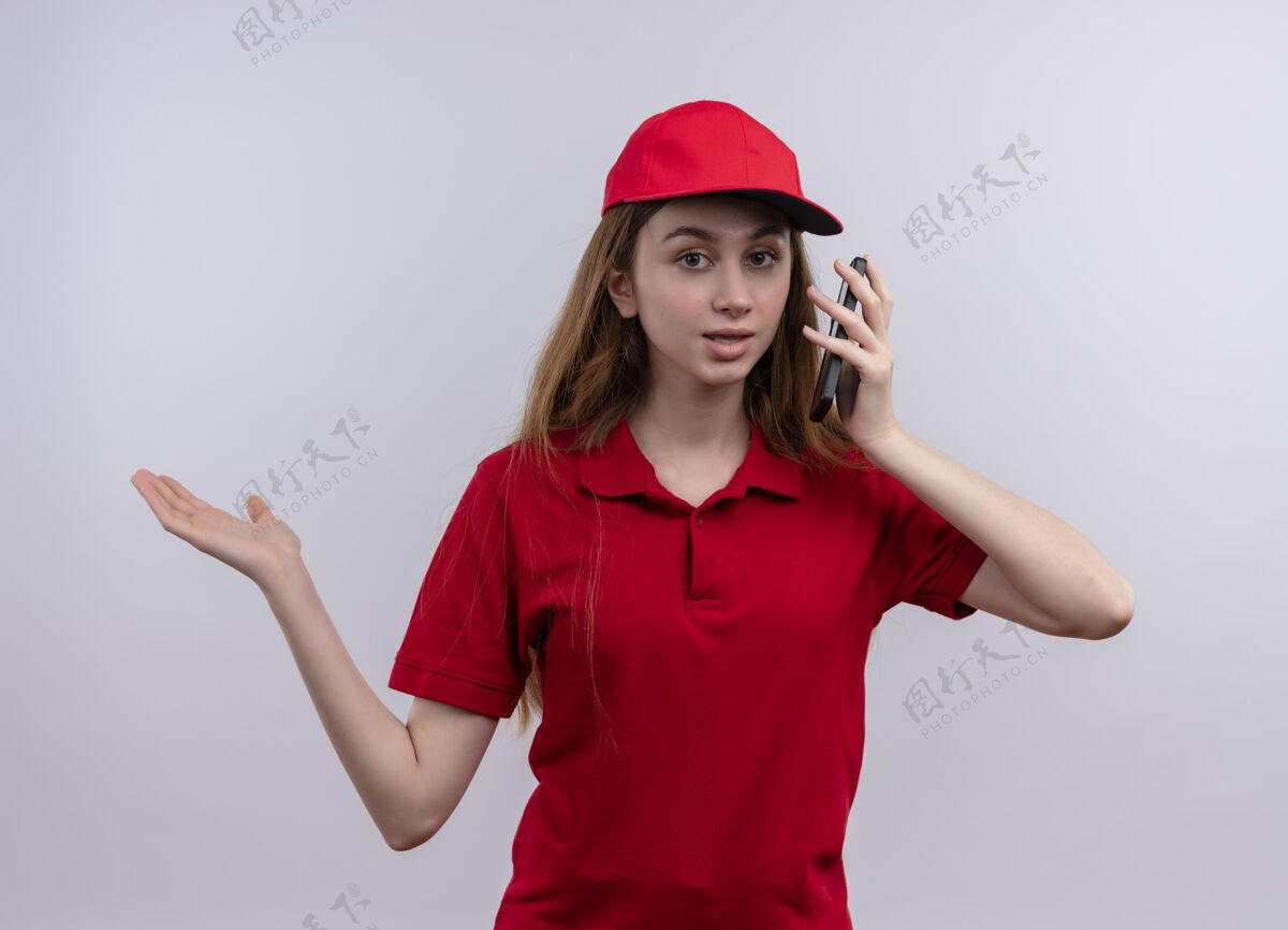 显示令人印象深刻的年轻送货女孩在红色制服手持手机 并显示空手孤立的白色空间电话印象红色