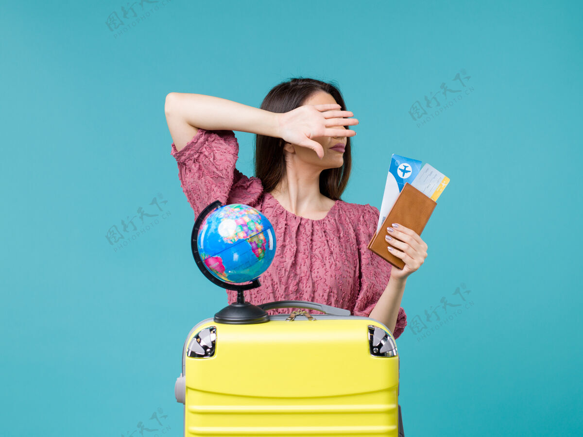 持有正面图度假中的女性拿着她的钱包和机票在蓝色背景海上旅行度假女性旅行钱包蓝色旅行