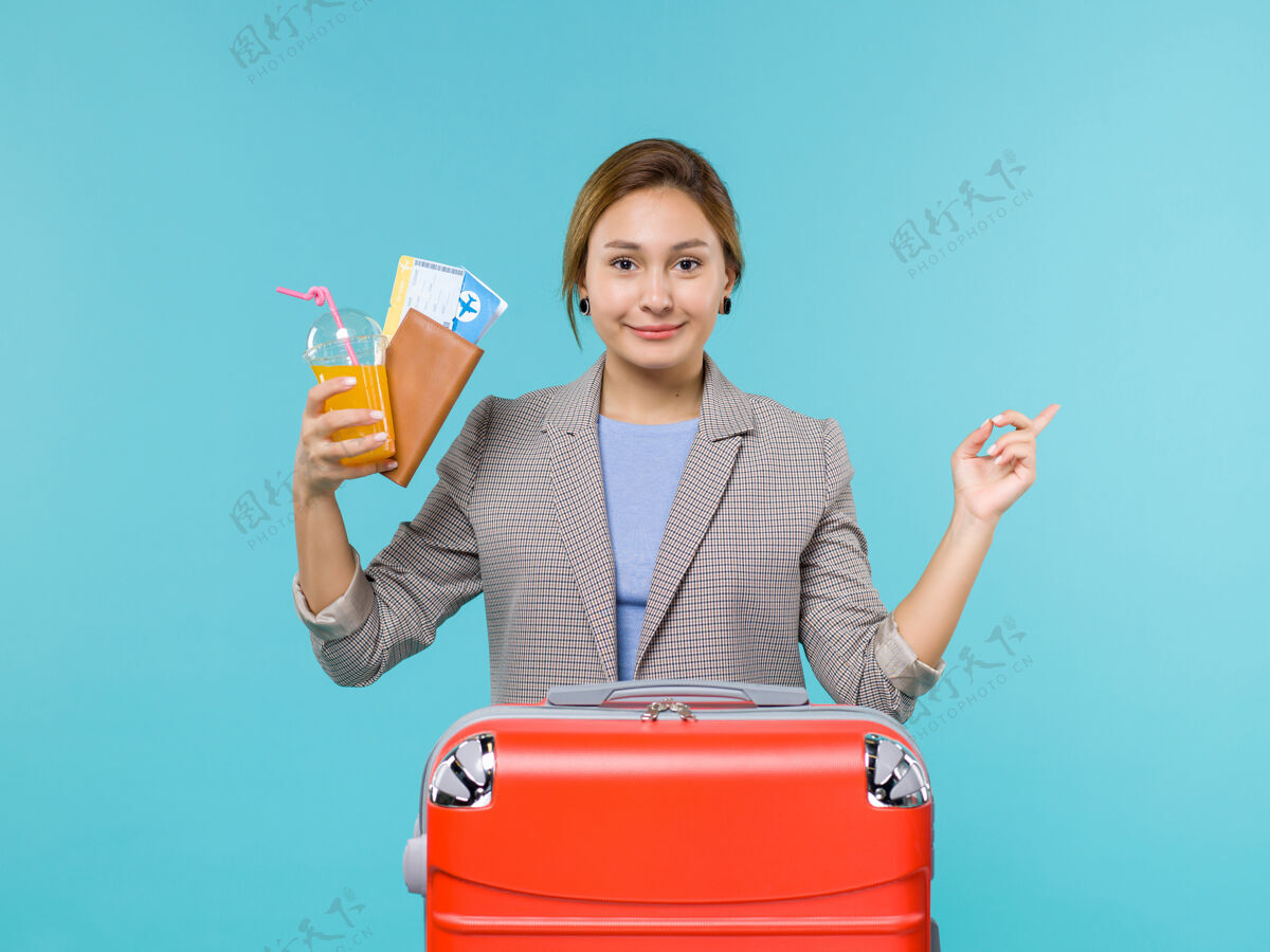 人前景度假女手持饮料和机票在蓝色背景海上旅行度假飞机旅行旅行航行蓝色假期