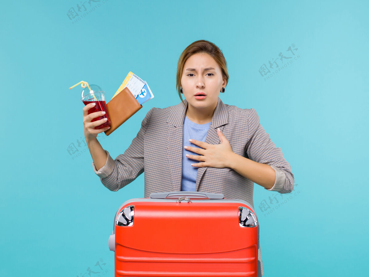 果汁前景度假中的女性拿着果汁和机票在蓝色背景上咳嗽旅行度假海上飞机看法旅行航行