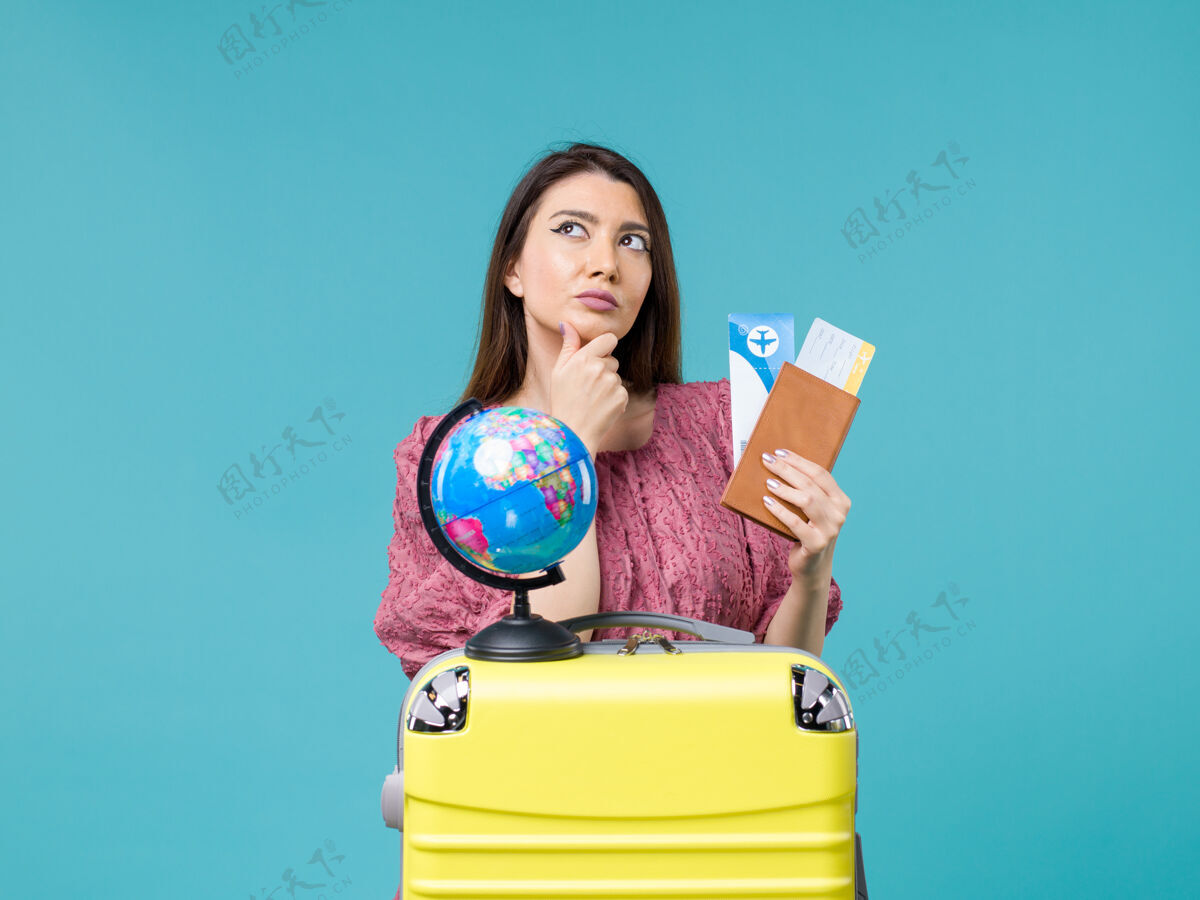 机票前视女在旅途中拿着钱包拿着机票想着蓝色背景的海女远航度假之旅钱包旅行人