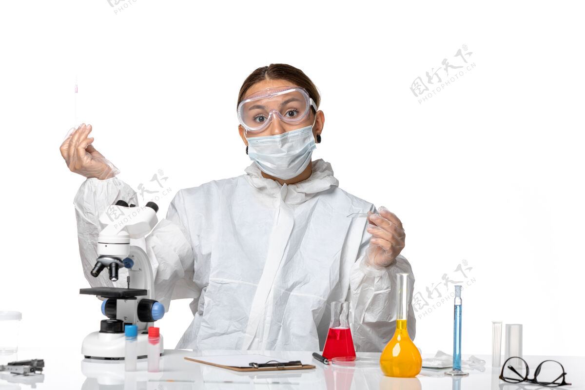 视图前视图穿着防护服 戴着口罩的女医生正在用白色背景病毒大流行冠状病毒的溶液工作实验室外套实验室外套