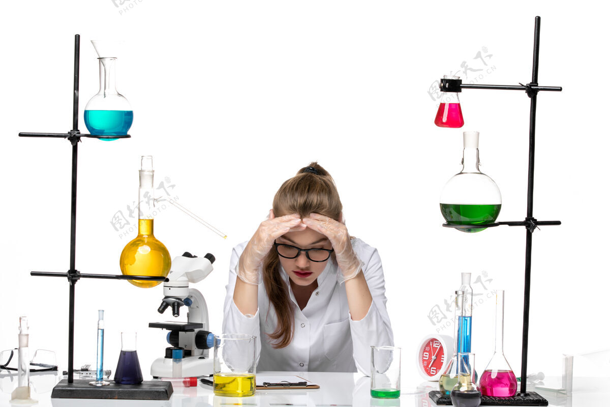 实验室前视图：身着医疗服的女化学家坐在桌子前面 白色背景上有溶液化学大流行性冠状病毒焦点医学病毒
