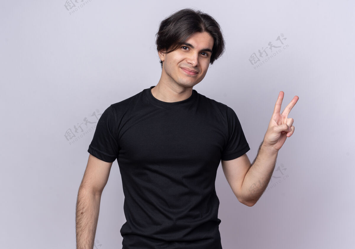 感觉高兴的年轻帅哥穿着黑色t恤 在白墙上显示和平姿态和平市民脸