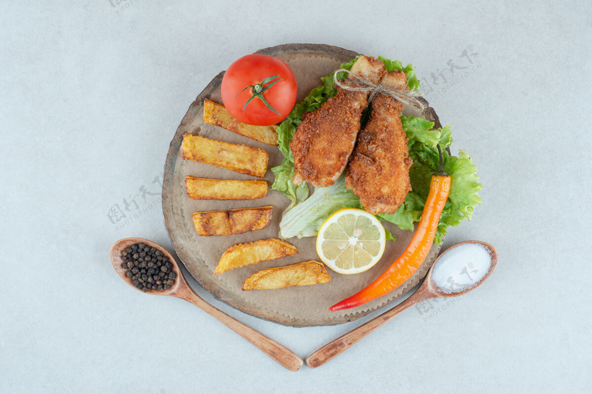 薯条大理石桌上放着一个木盘 上面放着油炸玉米饼和蔬菜生菜美味鸡肉
