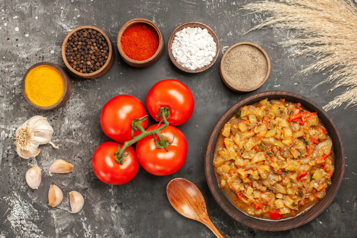 一餐顶视图烤茄子沙拉在碗里不同的香料碗大蒜番茄在黑暗的表面碗烹饪晚餐