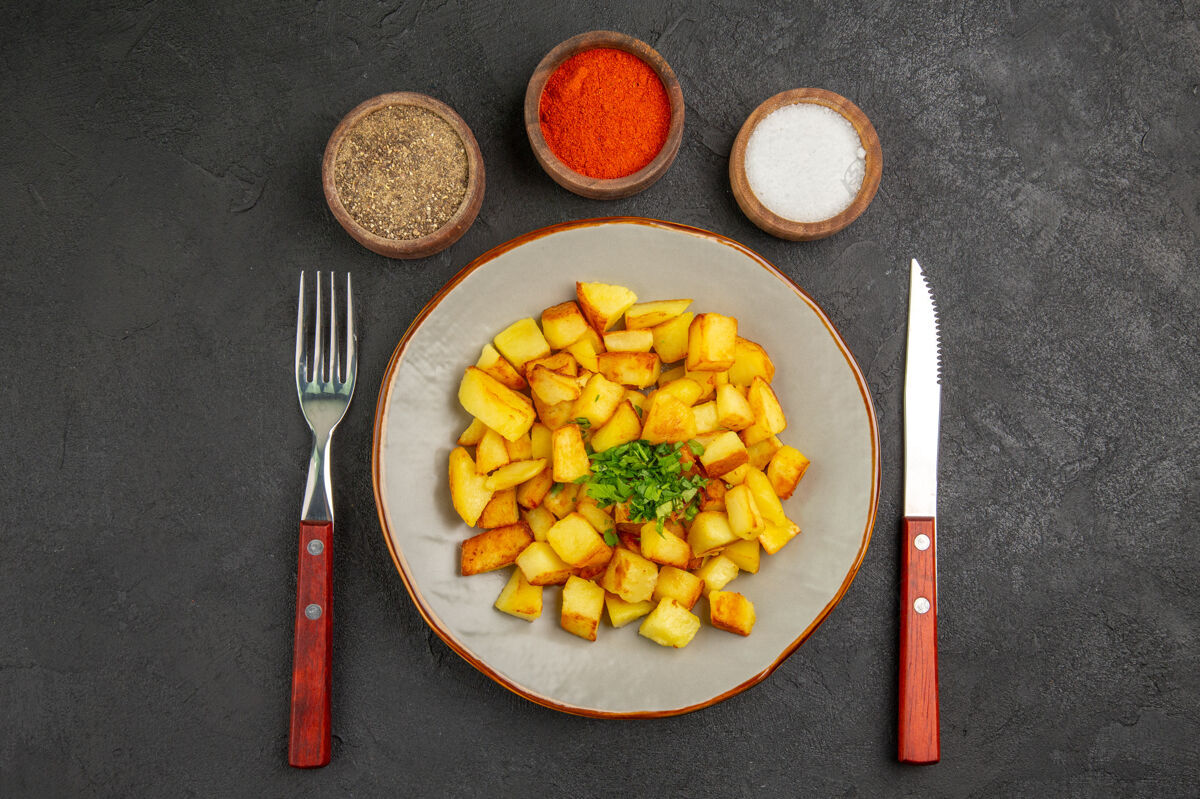 薯条美味的炸土豆在黑暗的表面与调味品盘子内俯视图午餐蔬菜油
