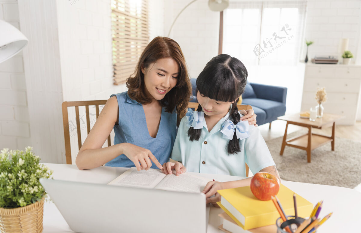 人在家上学的亚洲小女孩在家和妈妈一起坐在桌子上学习泰语学生亚洲人