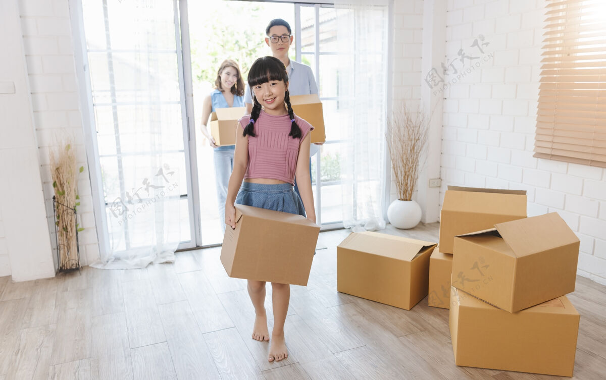 包装幸福亚洲人一家抱着纸板箱跑进新家搬迁概念亚洲女性房间