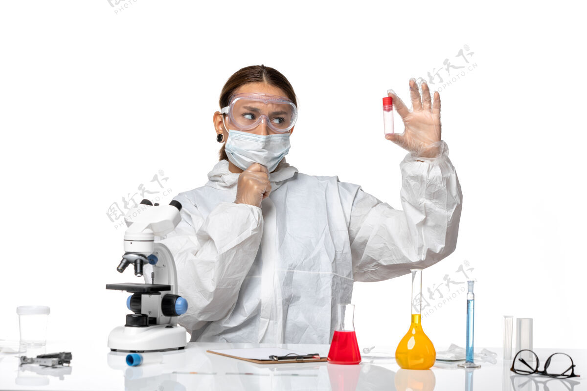 空正面图：女医生穿着防护服 戴着口罩 白桌子上拿着空烧瓶大流行病毒冠状病毒冠状病毒健康病毒健康套装